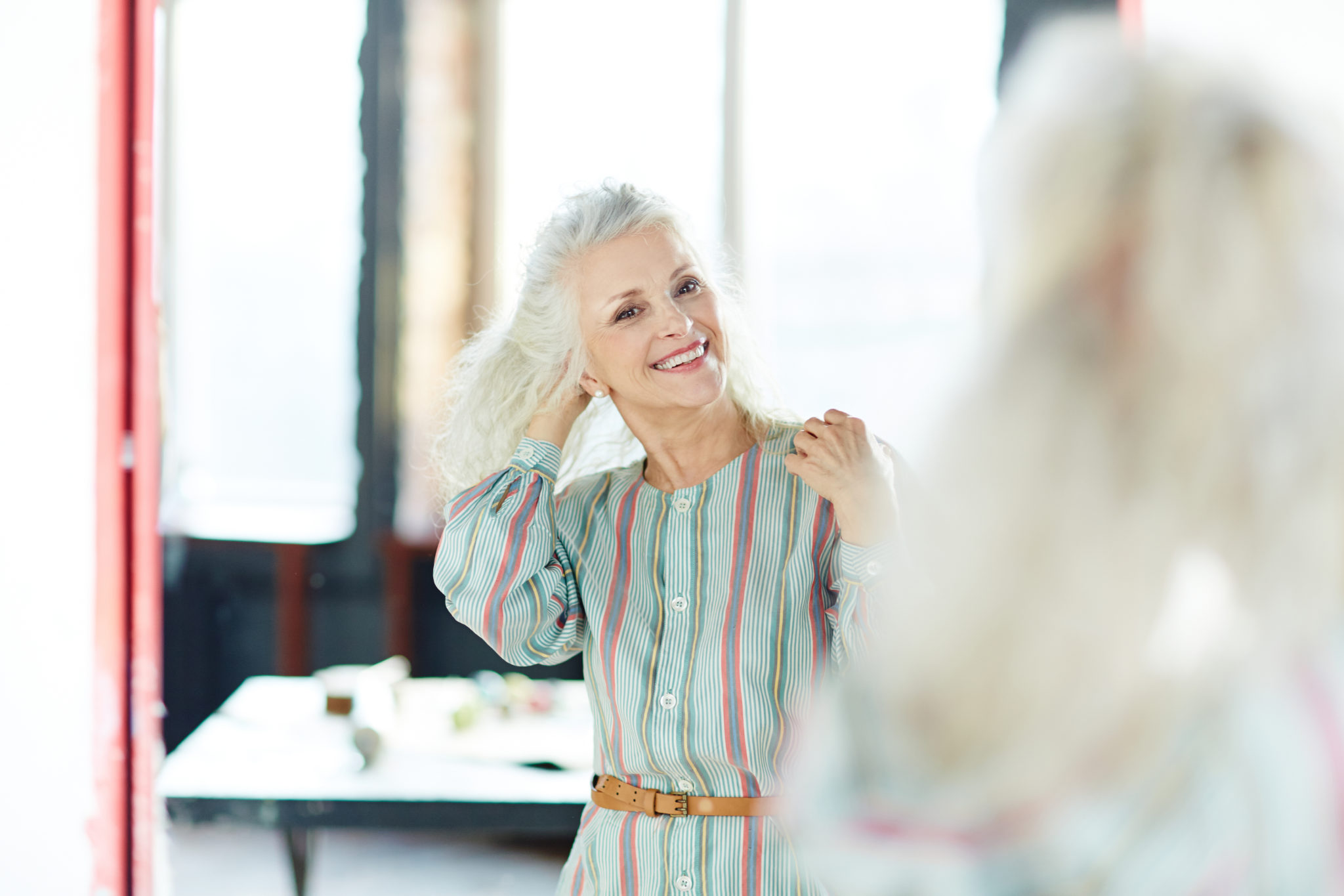 woman looks into mirror and smiles