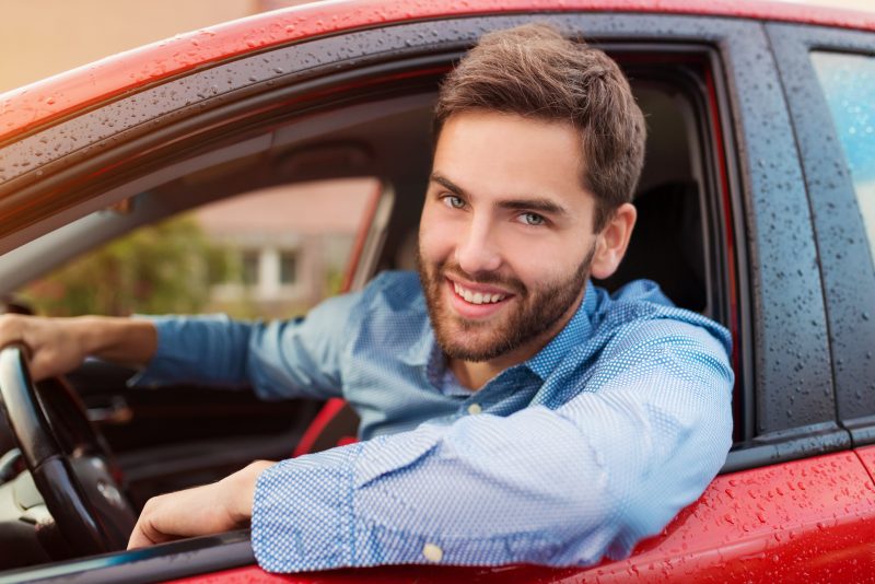 Handsome young man in a blue shirt driving a car