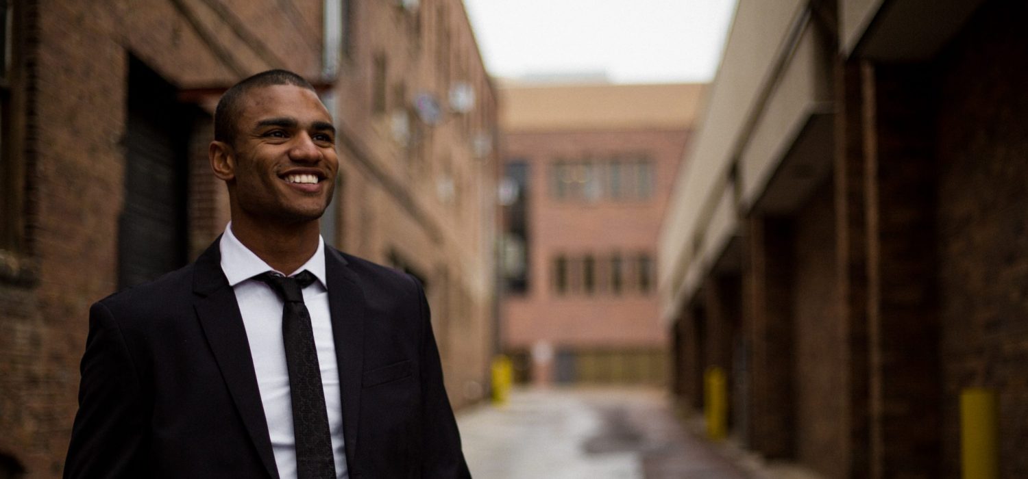 Young business walking in an alley, smiling